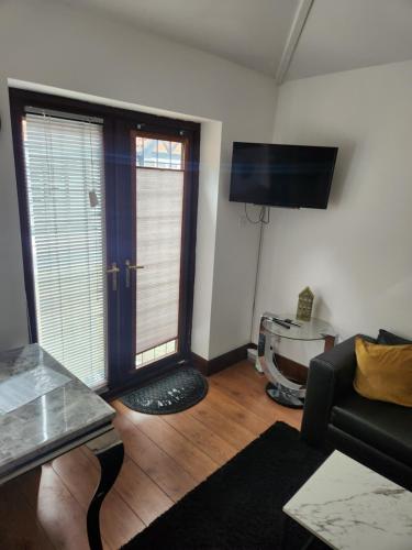 a living room with a couch and a flat screen tv at Cosy Studio Flat in Bexleyheath