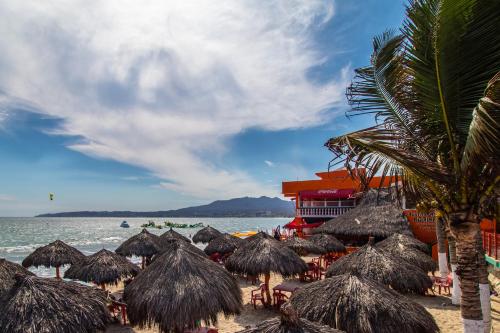 a beach with straw umbrellas and the ocean at Beach Loft LIFE Bucerías - Zona Dorada in Bucerías
