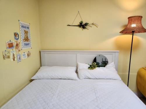 a bedroom with a bed with white pillows and a lamp at Lemontree in Seoul