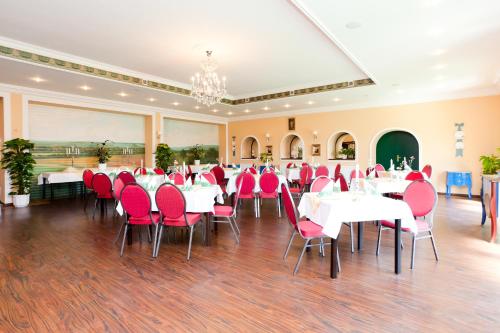 a banquet hall with white tables and red chairs at Gastwirtschaft & Hotel Hallescher Anger in Naumburg