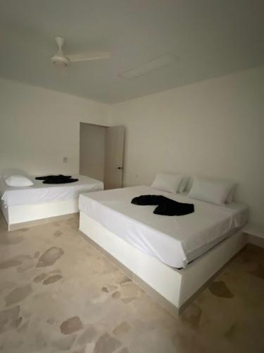 two white beds in a white room with at Cabañas Privadas en Playas del Francés con Piscina in San Silvestre