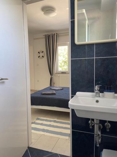 a bathroom with a sink and a bed with a mirror at Rab Island Apartmets - Palit in Rab