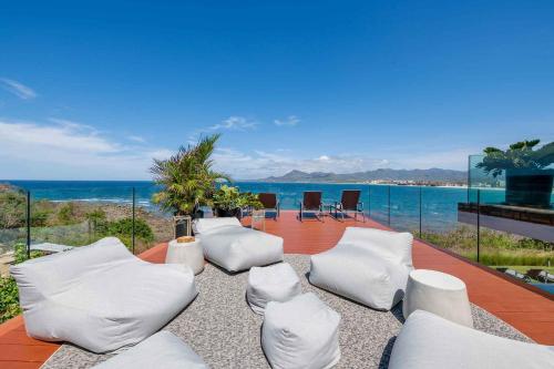 a living room with white chairs and the ocean at Beachfront house in Kupuri Punta Mita in Puerto Vallarta