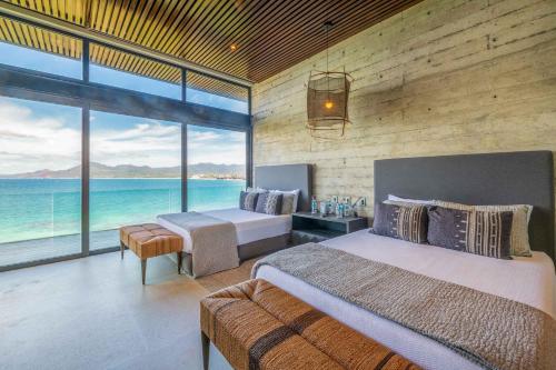 a bedroom with two beds and a view of the ocean at Beachfront house in Kupuri Punta Mita in Puerto Vallarta