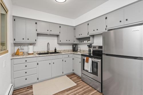 a kitchen with white cabinets and a stainless steel refrigerator at Modern Comfort Apartment in Great Falls in Great Falls