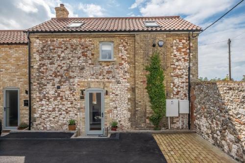 a brick house with a stone wall at In Focus in Titchwell