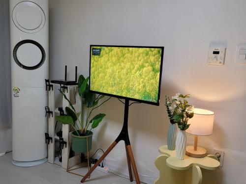 a flat screen tv on a tripod in a room with plants at Lemontree in Seoul