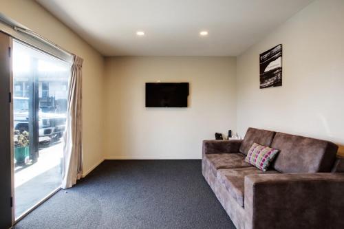 a living room with a couch and a tv at Ellerslie Palms Motel in Auckland