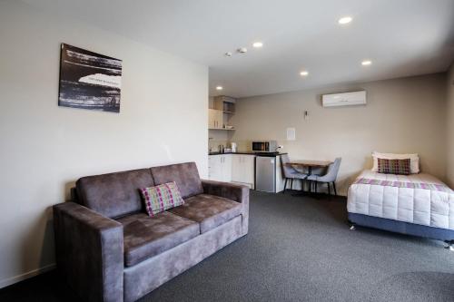 a living room with a couch and a bed at Ellerslie Palms Motel in Auckland