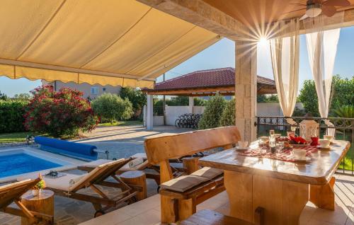 Un patio con mesa y sillas y una piscina. en Stunning Home In Vrsi With Sauna, en Vrsi