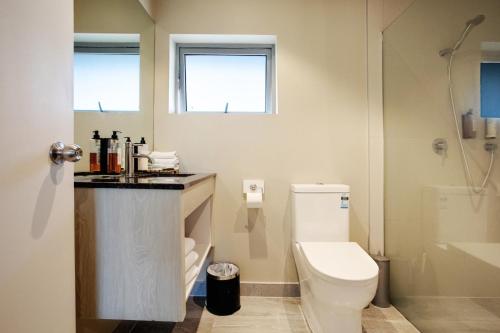 a bathroom with a toilet and a sink and a shower at Ellerslie Palms Motel in Auckland
