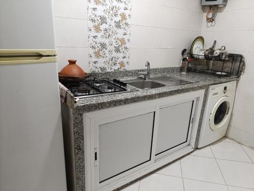 a kitchen with a sink and a washing machine at Appartement marhaba family only in Tangier