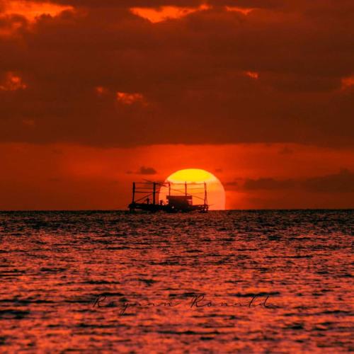 a boat in the ocean with a sunset at VidFauw Oasis Villa in Naamlong