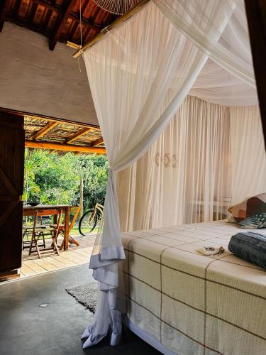 a bedroom with a canopy bed and a table at Casa da Mata Corumbau in Corumbau