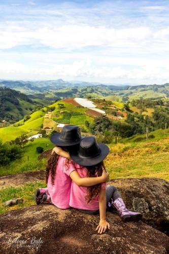 two girls wearing hats sitting on a rock at Chalé Serra dos tucanos in Gonçalves