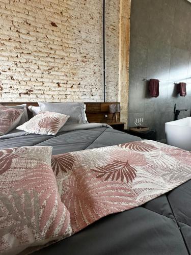 a bedroom with a bed and a brick wall at Vinícola Mirantus in Espirito Santo Do Pinhal