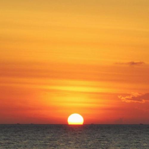 a sunset over the ocean with the sun in the sky at VidFauw Oasis Villa in Naamlong