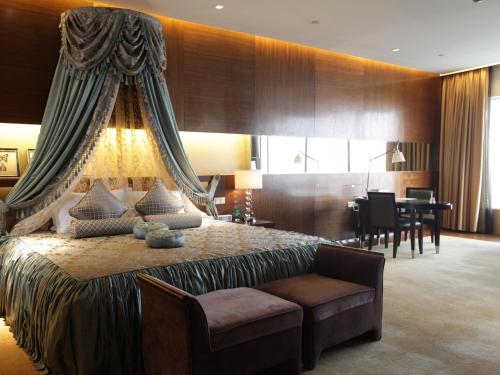 a bedroom with a large bed with a chair and a desk at HJ International Hotel in Dongguan