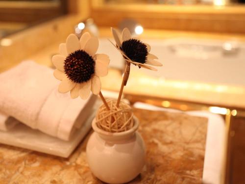 two flowers in a white vase on a table at HJ International Hotel in Dongguan