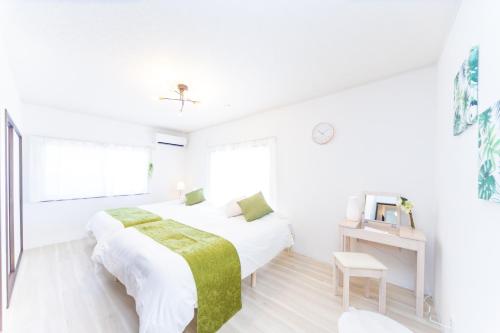 a white bedroom with two beds and a tv at Miraie Kuwana simofukayabe in Kuwana