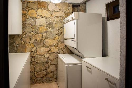 a white refrigerator in a kitchen with a stone wall at LA ROCA 8 min WALKING DISTANCE TO THE BEACH in San José del Cabo