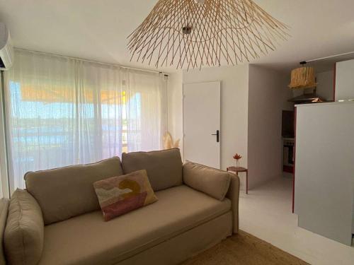- un salon avec un canapé et un lustre dans l'établissement Appartement rénové avec climatisation, terrasse et parking privé - FR-1-731-96, au Grau-du-Roi