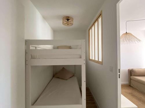 Ce lit superposé blanc se trouve dans une chambre blanche. dans l'établissement Appartement rénové avec climatisation, terrasse et parking privé - FR-1-731-96, au Grau-du-Roi