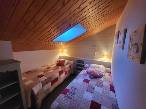 une chambre mansardée avec deux lits et une lucarne dans l'établissement Superbe appartement 3 chambres sur les pistes de Montgenèvre, parking inclus - FR-1-266-233, à Montgenèvre