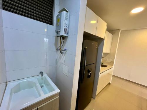 Una pequeña cocina con fregadero y refrigerador. en 403 - Samaria Club de Playa, en Gaira