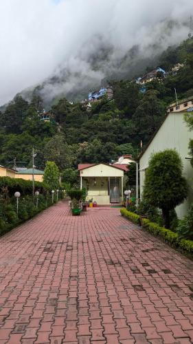 a brick road with a building and a mountain at Ashirwad residency in Dhārchula