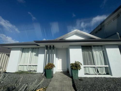 a white house with two windows and two plants at Golfers dream 300m to the beach in Dawesville