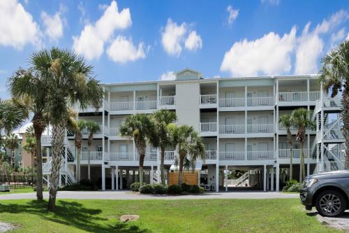 a large white building with palm trees in front of it at Dunes Club 1A by Pristine Properties Vacation Rentals in Cape San Blas