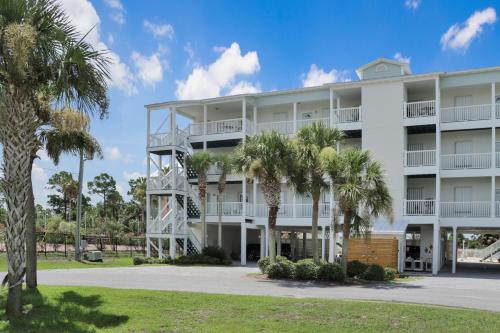a large white building with palm trees in front of it at Dunes Club 1A by Pristine Properties Vacation Rentals in Cape San Blas