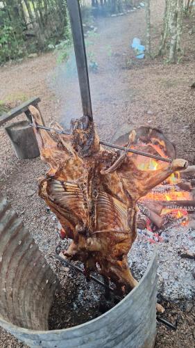 a piece of meat is cooking over a fire at Cabaña en Rio Puelo in Puelo