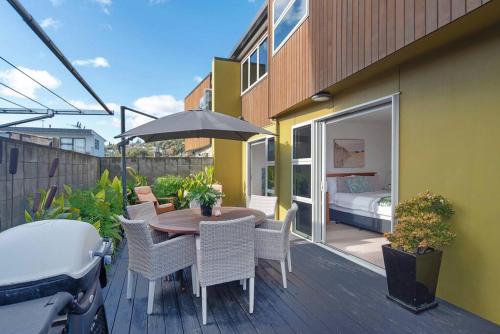 a patio with a table with chairs and an umbrella at Tahuna Beach Oasis in Nelson