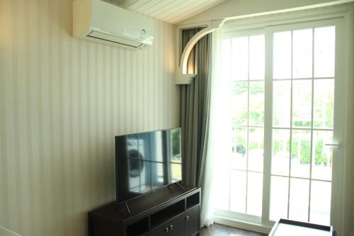 a living room with a tv and a window at Grand Florida芭提雅带免费游泳池温泉桑拿浴和健身房瑜伽室私家海滩公寓E206 in Na Jomtien