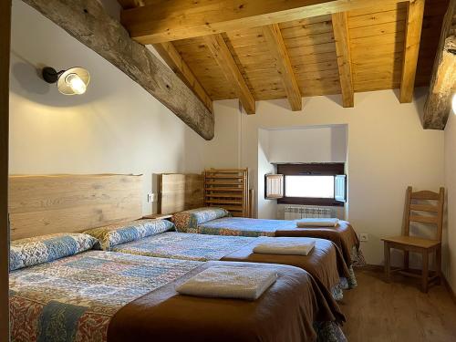 two beds in a room with wooden ceilings at Palacio de Aralar Terracita in Oskotz