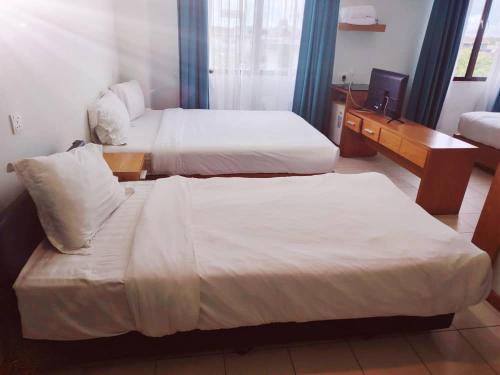 a hotel room with two beds and a desk at Fratini's Hotel Labuan in Labuan
