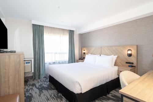 a hotel room with a bed and a desk at Sandman Hotel & Suites Regina in Regina