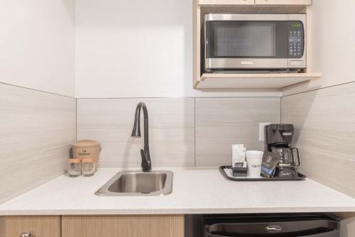 a kitchen with a sink and a microwave at Sandman Hotel & Suites Regina in Regina