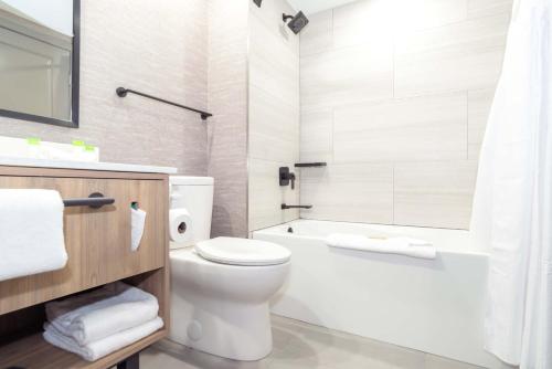 a bathroom with a toilet and a tub and a sink at Sandman Hotel & Suites Regina in Regina