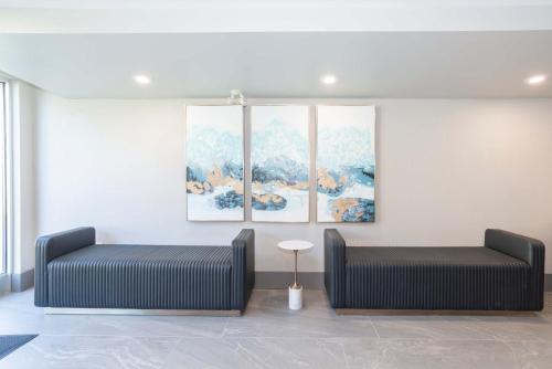 two beds in a room with paintings on the wall at Sandman Hotel & Suites Regina in Regina