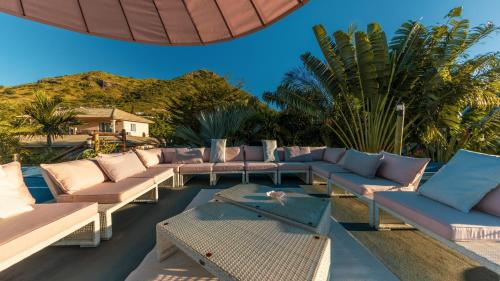 a patio with couches and a table and an umbrella at Villa Sartelo in Tamarin