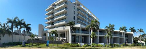 a building with palm trees in front of it at Zantamar La Cruz Beach & Pool in Cruz de Huanacaxtle