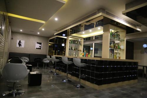 a bar with a bunch of stools in a room at Hotel Atrium in Erode