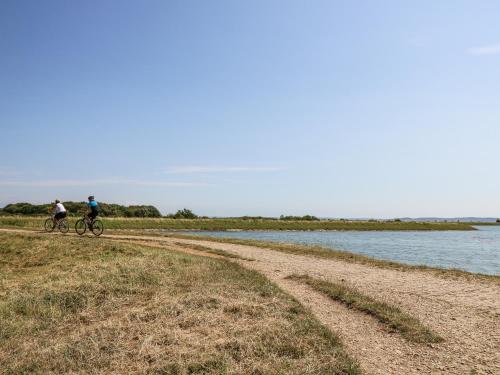 two people riding bikes on a dirt road next to a river at Lymington Lodge in Lymington