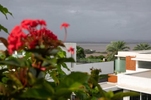 a view of the ocean from a building with red flowers at Casa De Fiesta at Vasco Da Gama by StayVista in Dabolim