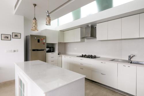 a kitchen with white cabinets and a stainless steel refrigerator at Casa De Fiesta at Vasco Da Gama by StayVista in Dabolim