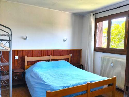 - une chambre avec un lit doté de draps bleus et d'une fenêtre dans l'établissement Charmant 3 pièces: balcon, parking privé, proche village - FR-1-761-42, à Villard-de-Lans