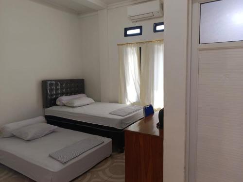 Dos camas en una habitación pequeña con ventana. en Sibento Komodo Homestay, en Labuan Bajo